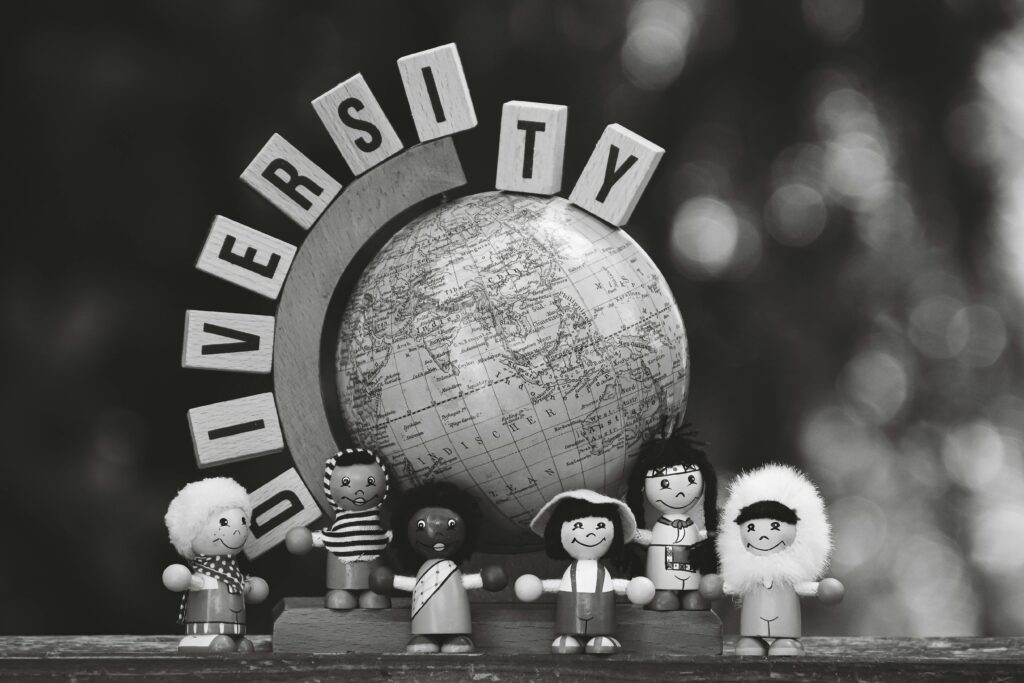 Black and white image of diverse wooden dolls and a globe representing cultural diversity.