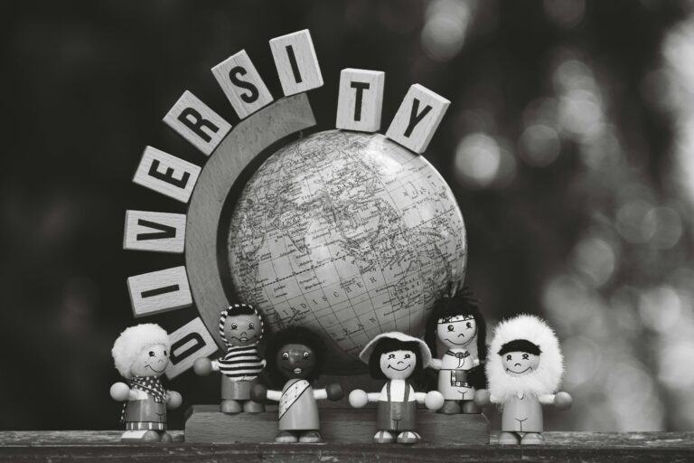 Black and white image of diverse wooden dolls and a globe representing cultural diversity.